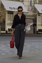 a lady in a black cut-out shirt and a pair of grey wide leg pants